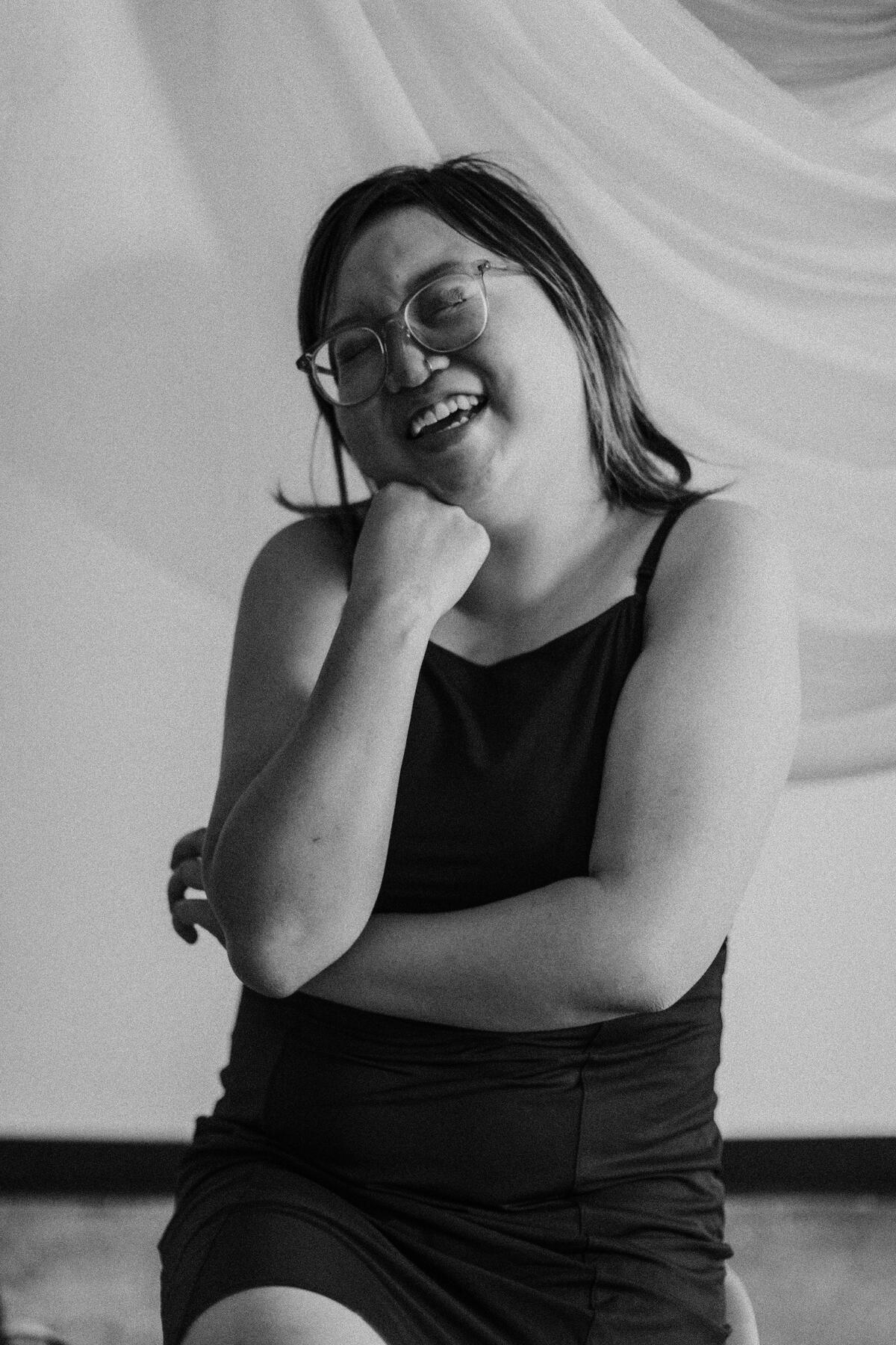 Sydney is a light skinned Chinese American person with a colorful glasses and medium length black hair with hints of purple framed highlights.